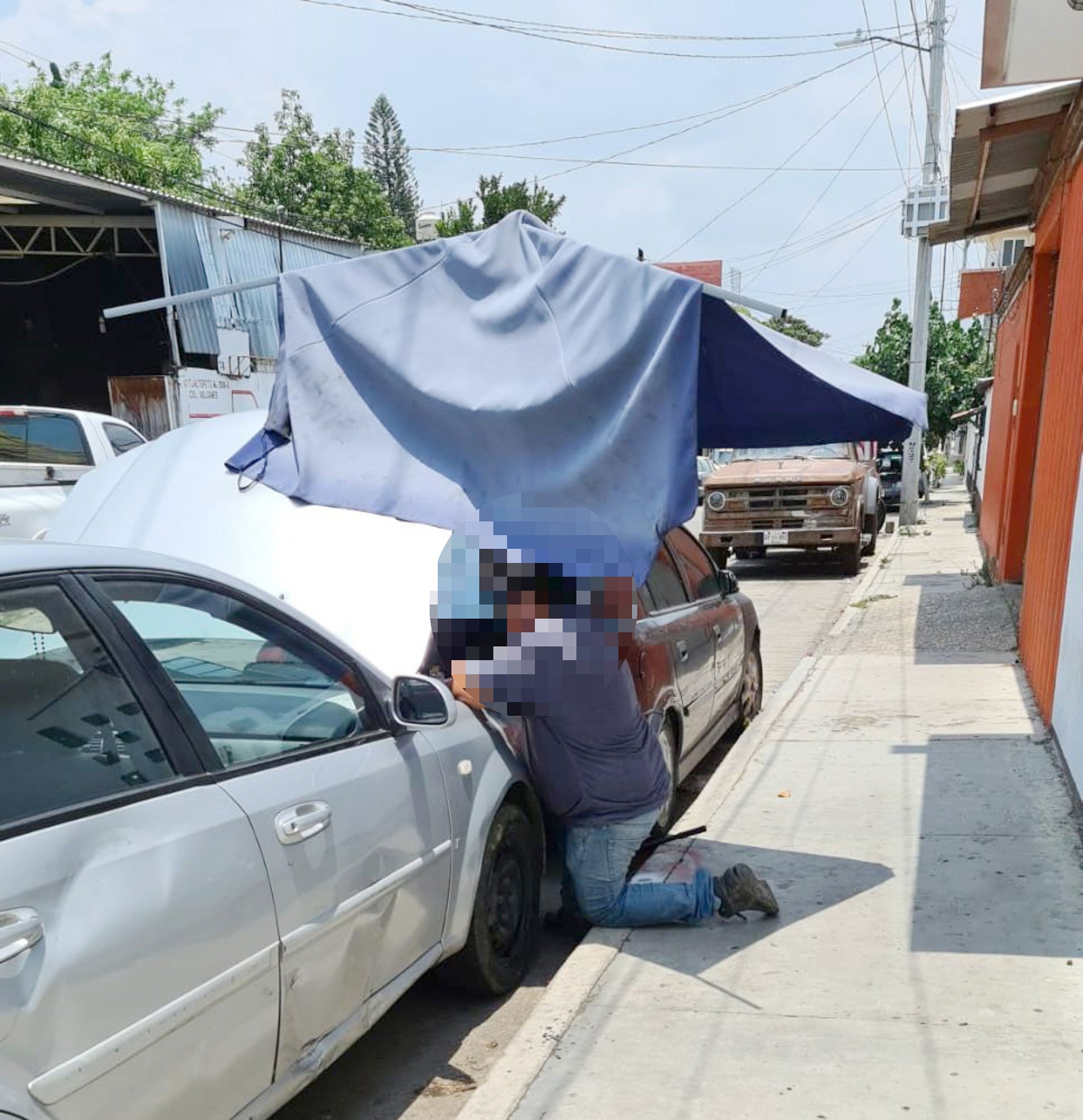 Los trabajadores de este taller de hojalatería realizan sus labores en plena vía pública.