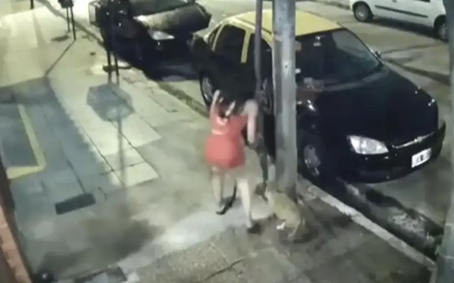 Una mujer acompañada de un niño apresuradamente ata al cachorro en un poste de la calle. 