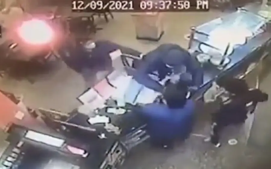 El cuerpo del delincuente quedó recostado sobre la caja registradora, mientras todos los presentes se alejan de la escena.