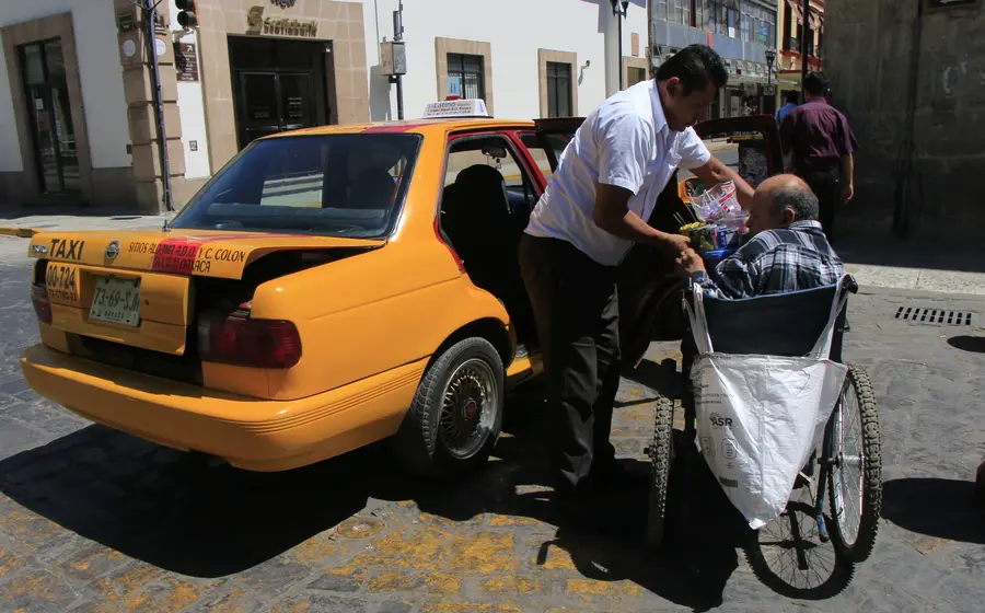 Persona en silla de ruedas abordando taxi