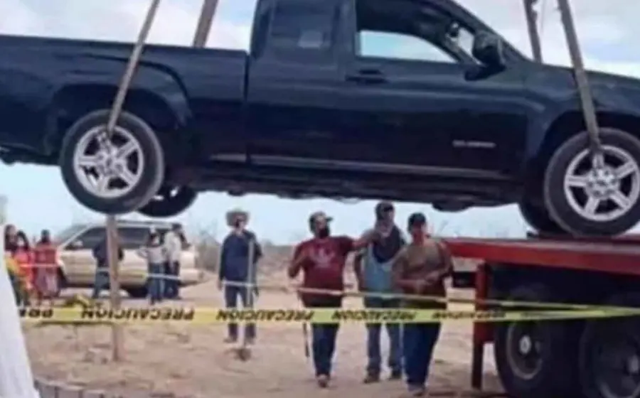 El material permite ver cómo introducen una camioneta negra, modelo Chevrolet Colorado 2005, en una fosa con block y cemento ayudados de una grúa. 