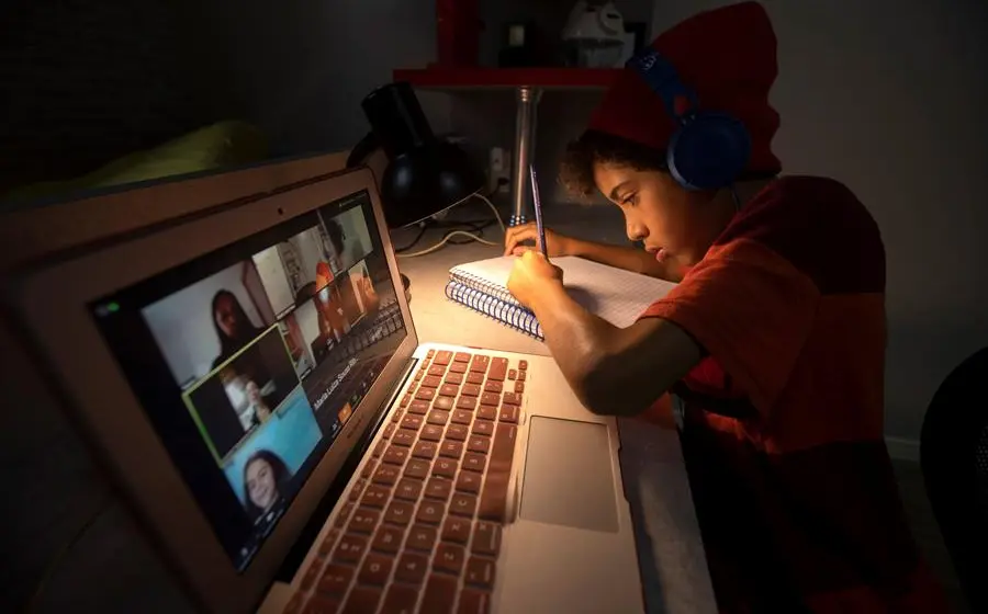 Niño escribiendo junto a computadora