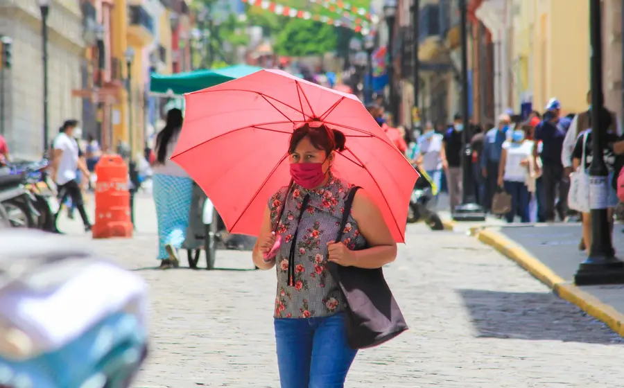 Mujer con cubrebocas y paraguas.