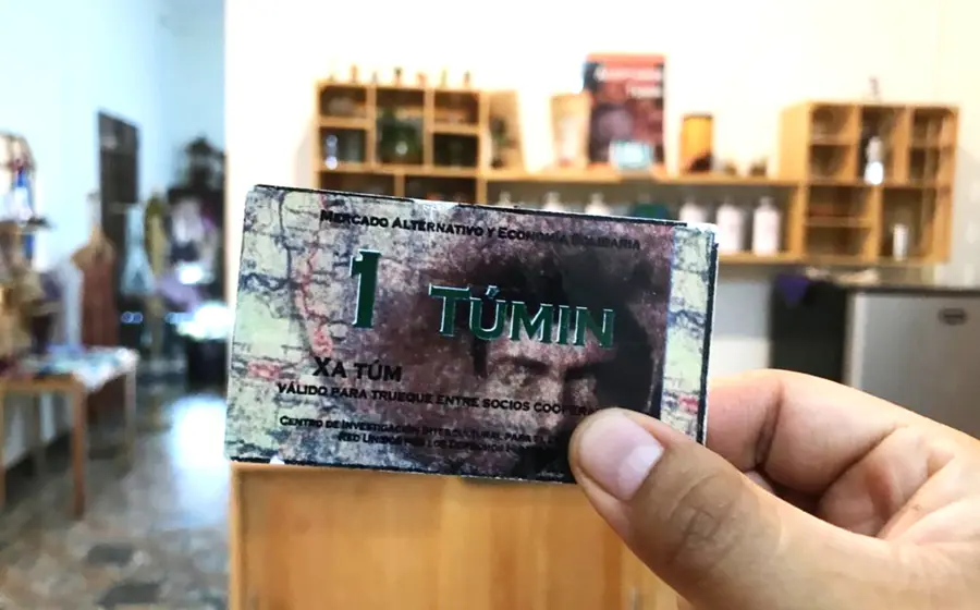 Billete de un tuním con cafetería de fondo.