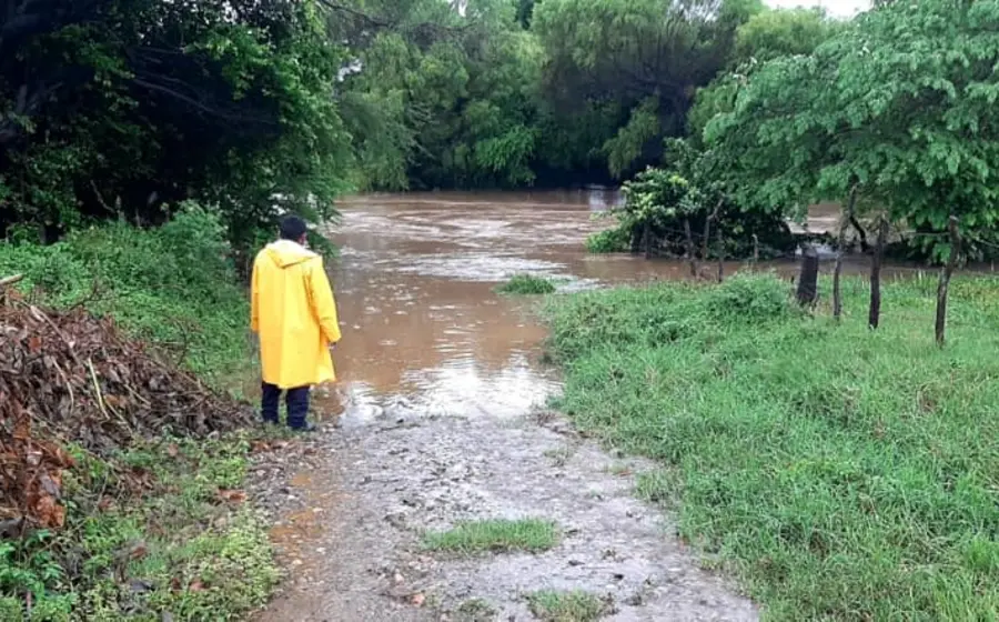 Persona con impermeable frente a río acaudalado