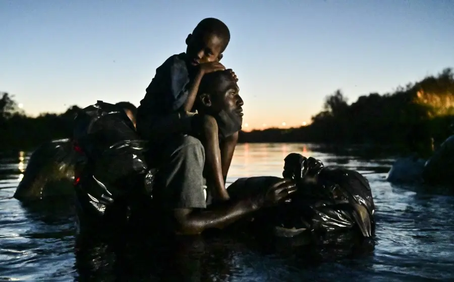 Migrantes haitianos cruzando un río