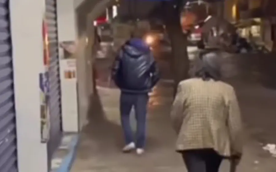 El supuesto hijo avanza sin decir nada, pues únicamente se le observa caminar con los hombros bajos y las manos en los bolsillos.