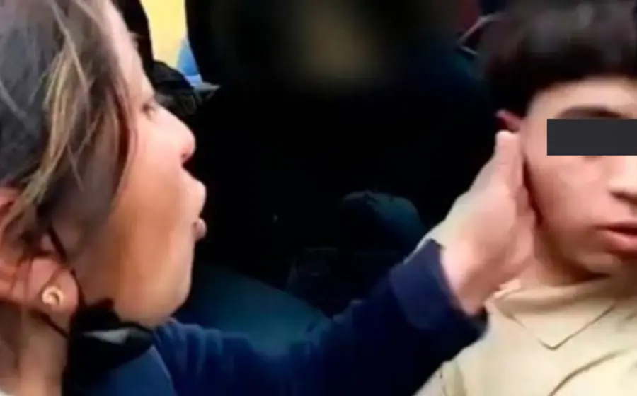 La mujer da cachetada a su hijo quien no dice alguna palabra.