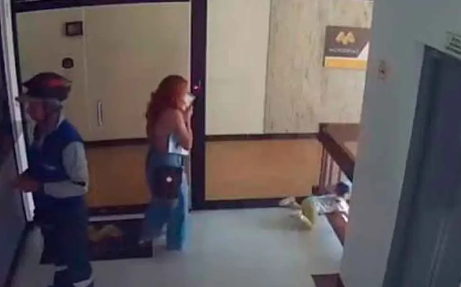 En centésimas de segundo, la madre, quien llevaba una bolsa en una mano y hablaba por teléfono con la otra, arroja todo y mediante un espectacular salto alcanza a sujetar el pie de su pequeño.