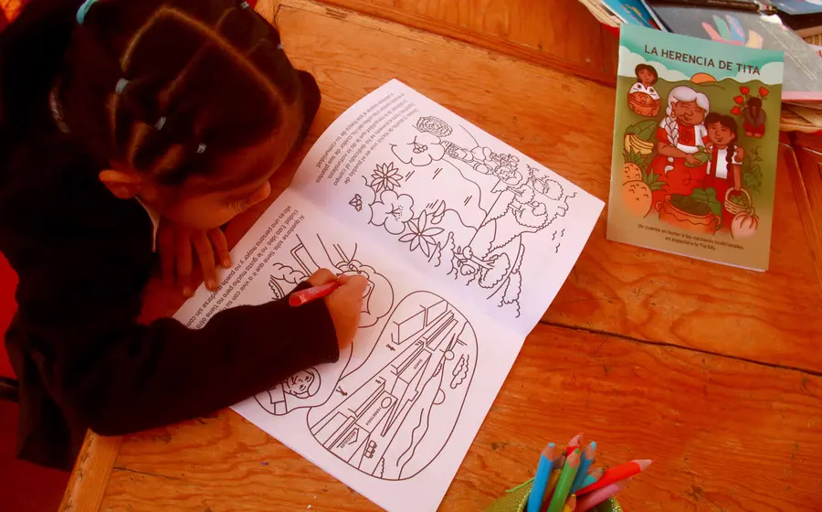 Una alumna de segundo grado de preescolar colorea el cuento La Herencia de Tita que honra el trabajo de alimentación sana de las cocineras tradicionales.