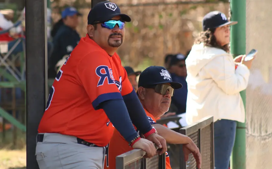 El mánager y un coach de los Yankees conversan en el dugout durante un partido de playoffs en busca del pase a la Serie Final.