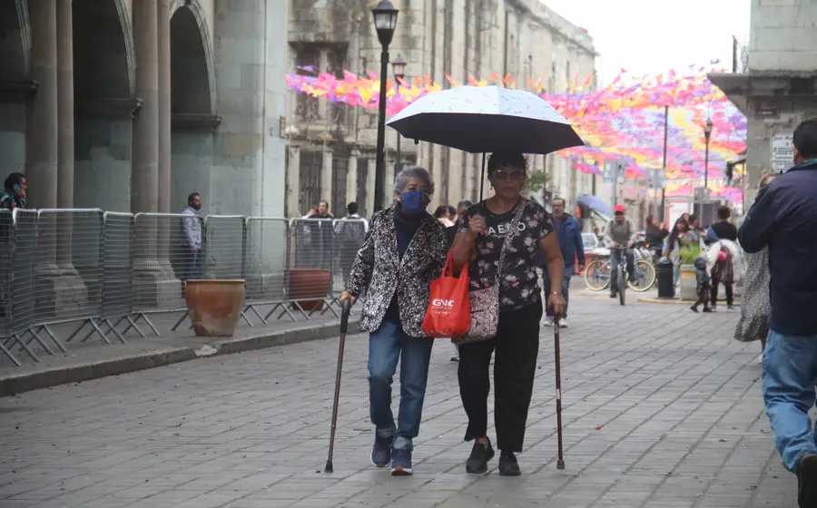 Una persona bien abrigada con gorro y bufanda representa la llegada de un nuevo frente frío que causará un descenso en las temperaturas.