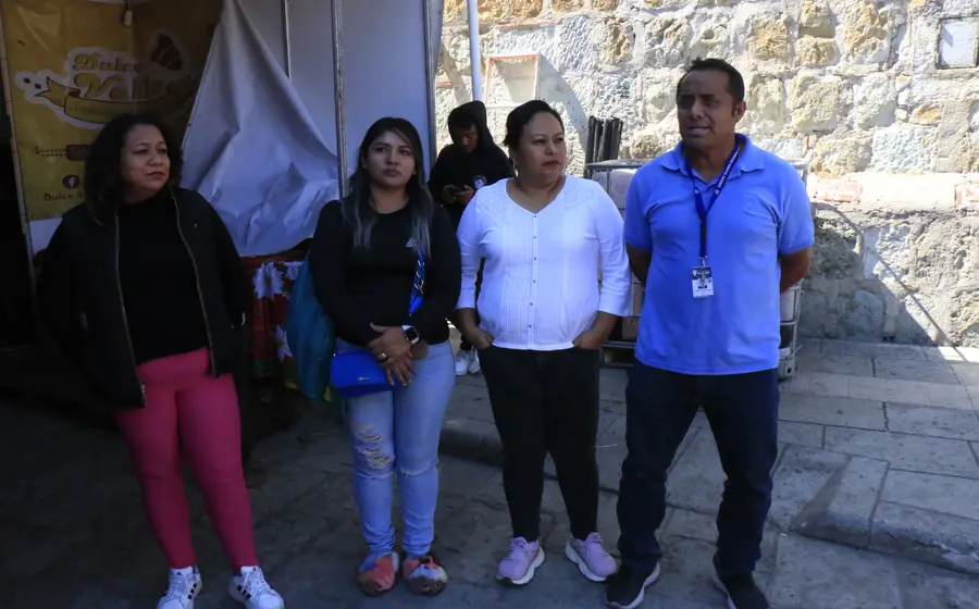 Varios puestos de vendedores ambulantes instalados sobre la banqueta justo en la entrada de una escuela primaria, obstaculizando el paso y generando riesgo para los alumnos.
