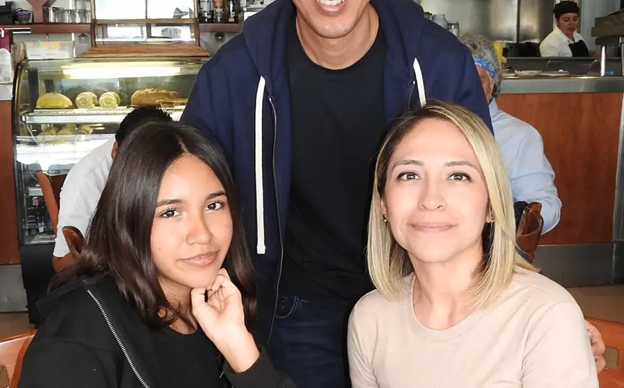 Renata Ceballos, Olga Vásquez y Óscar Ceballos sonríen juntos mientras disfrutan de un agradable momento con un café en un evento social.