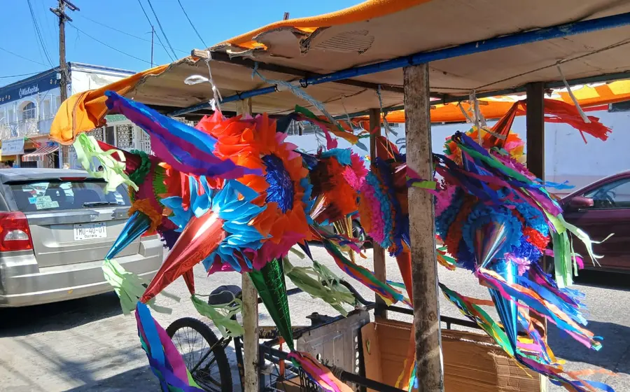 Una colorida exhibición de piñatas navideñas tradicionales, con sus característicos picos de estrella, colgadas en un puesto para su venta.