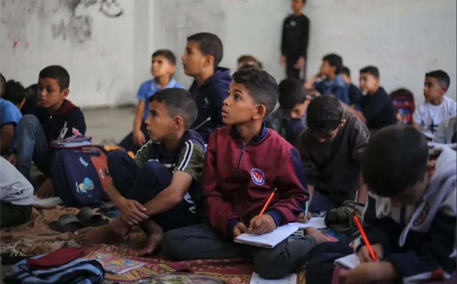 Los estudiantes toman lecciones en el suelo con el cuaderno en las rodillas. Foto: Afp