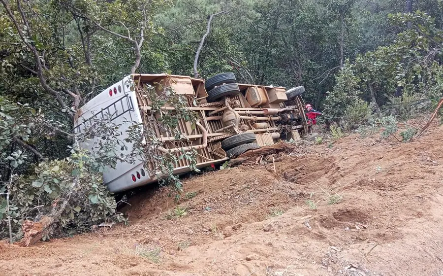Un autobús de pasajeros volcado se encuentra a un costado de la carretera local en Peñoles, tras el accidente vehicular.