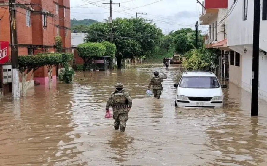Una calle inundada con autos parcialmente cubiertos por el agua, ilustrando los daños materiales causados por las intensas lluvias en México.
