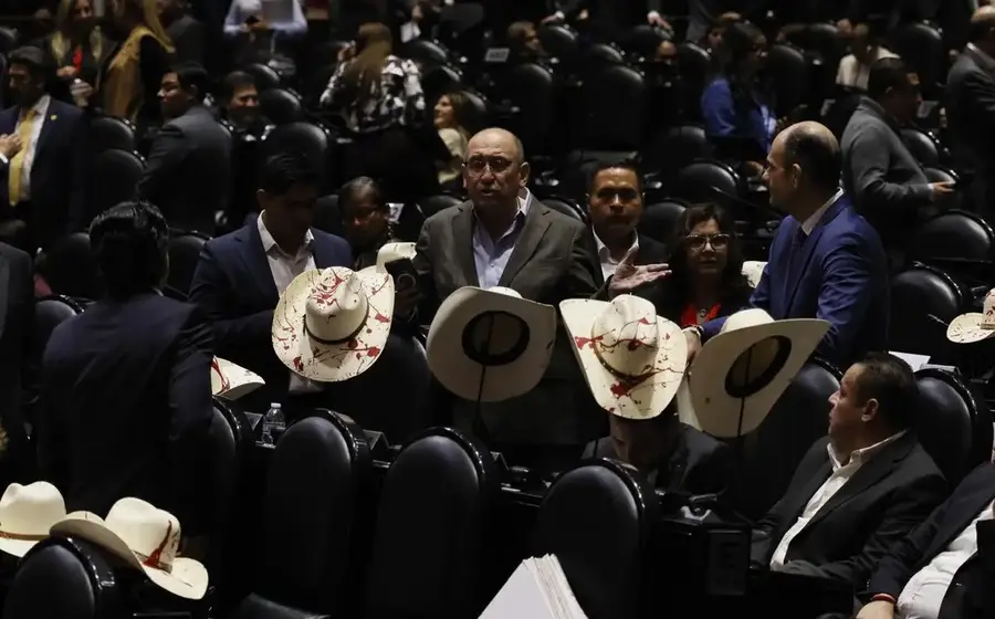 Diputados con sombreros manchados de rojo guardan un minuto de silencio y aplauden en memoria del presidente municipal de Uruapan, Carlos Manzo.