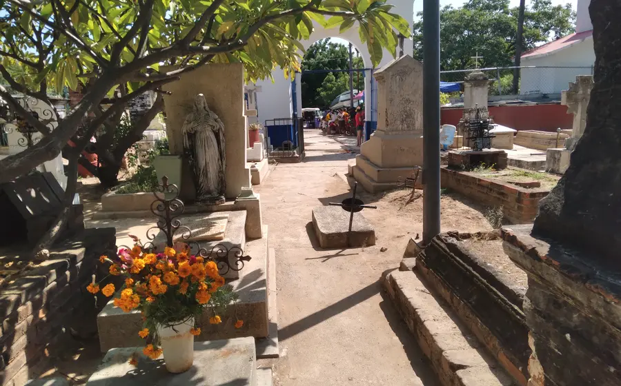 Familias y dolientes acuden a un camposanto para limpiar y adornar las tumbas de sus difuntos en la temporada de Día de Muertos.