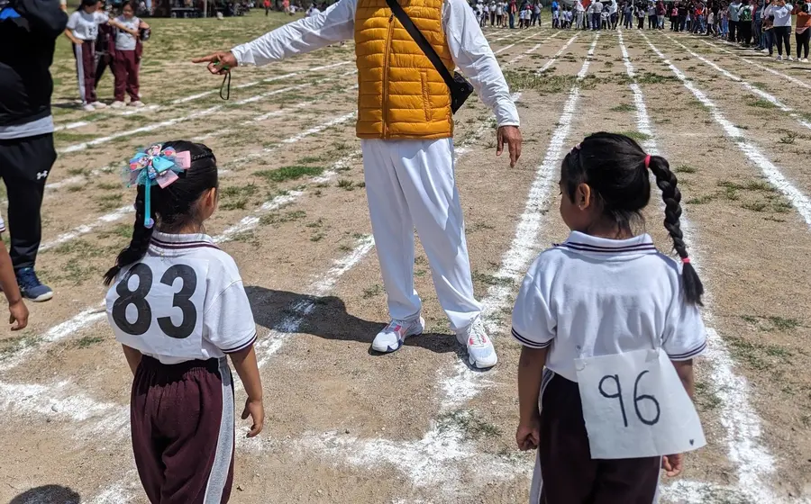 Estudiantes de primer ciclo compiten en las pruebas de pista y campo durante el evento de atletismo de las Mini Olimpiadas.