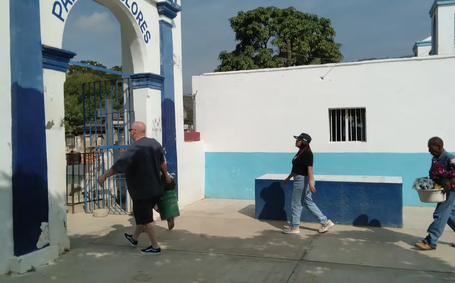 Una multitud de personas y familias caminan entre las tumbas de un panteón municipal, mostrando la gran afluencia de visitantes.