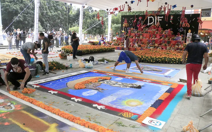 Una colorida exposición de altares y tapetes tradicionales como parte de las festividades del Día de Muertos, invitando a vivir 'La fiesta más viva de todas'.