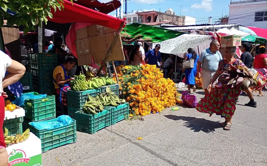 Un puesto en un mercado local exhibe y vende productos de temporada, como flores y adornos, para las próximas celebraciones del Día de Muertos.