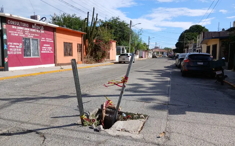 Una alcantarilla abierta en Tehuantepec es señalizada con palos y piedras por habitantes para alertar del peligro a transeúntes y automovilistas.