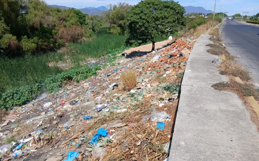 Una gran acumulación de basura y desechos en un tiradero clandestino que crece a un costado de una carretera, generando un foco de contaminación.