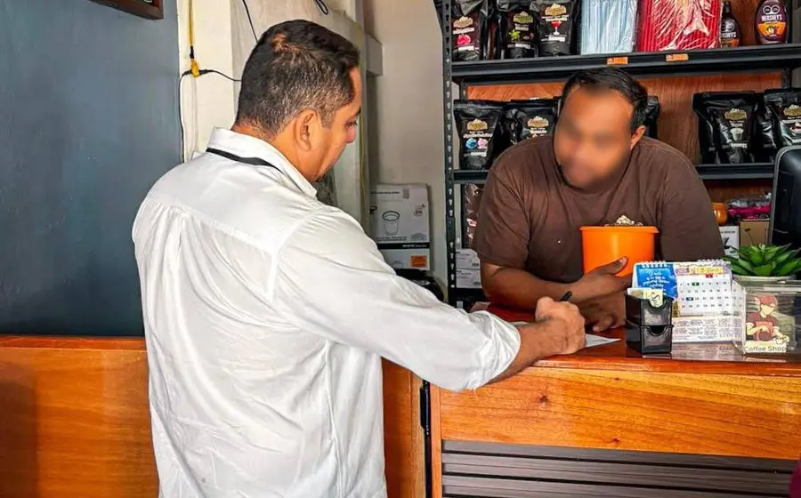 Un funcionario revisa la licencia sanitaria de un comercio en Juchitán, documento que garantiza el cumplimiento de las normas de higiene.