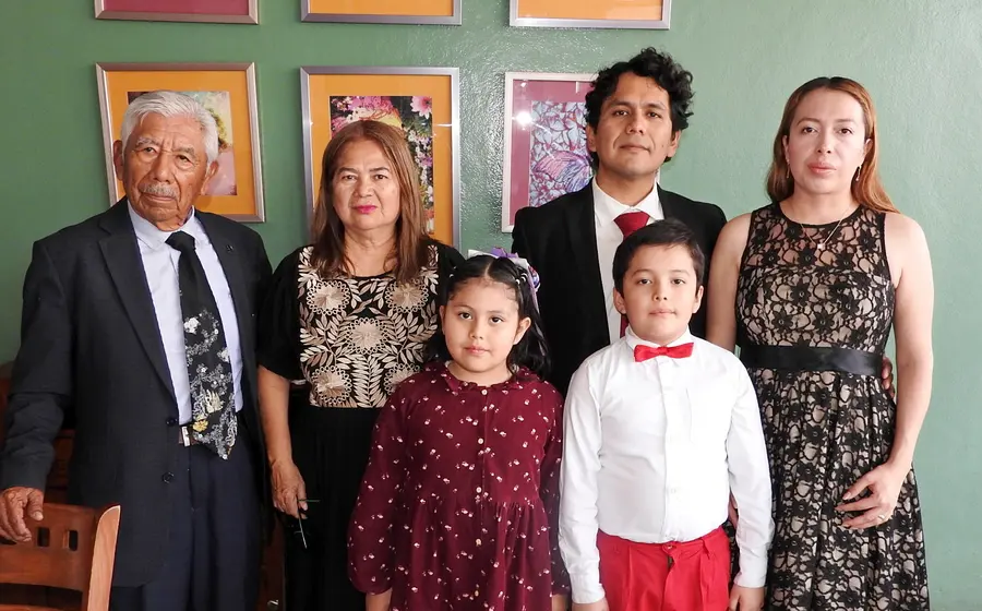 El doctor Adalid Juan Osorio celebra la culminación de su especialidad en Ginecobstetricia, posando sonriente junto a su esposa, hijos y padres.