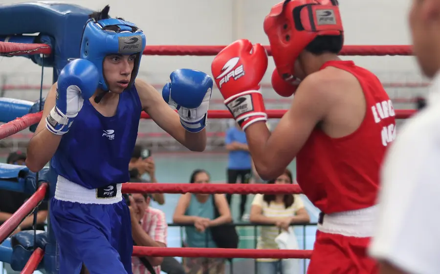 Dos jóvenes boxeadores intercambian golpes durante un aguerrido combate en el Campeonato Estatal de Boxeo, clasificatorio para el Festival Olímpico.