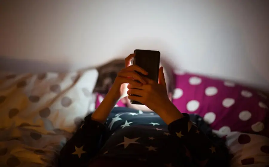 Un joven absorto en la pantalla de su teléfono, representando la falta de control sobre el tiempo de uso que afecta a casi la mitad de los menores.