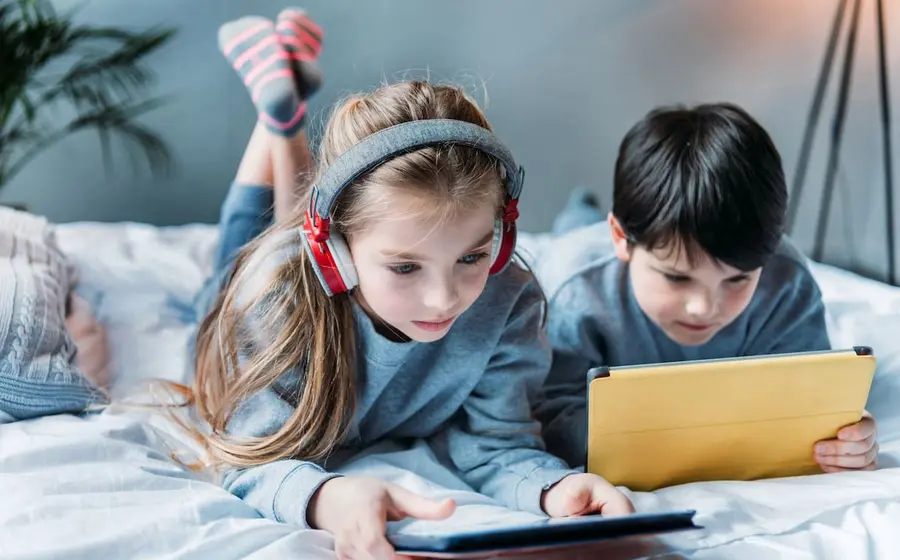 Un niño se entretiene viendo contenidos audiovisuales en una tableta, reflejando una de las actividades recreativas infantiles más comunes actualmente.