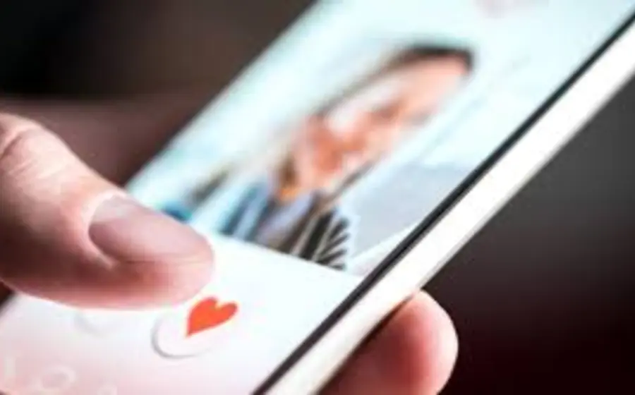 Una persona revisa su teléfono con una aplicación de citas, ilustrando los riesgos y el lado oscuro de buscar pareja en línea, como el chantaje.