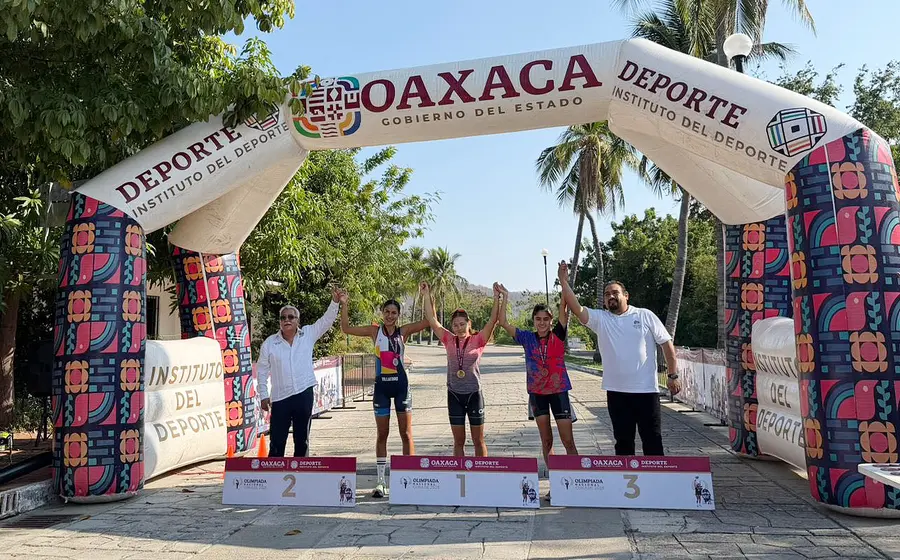 Las tres atletas ganadoras de los primeros lugares en la rama femenil del duatlón posan juntas en el podio de premiación.