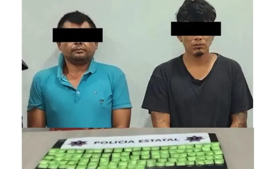 Los dos sujetos detenidos son presentados ante la cámara junto a las 100 dosis de droga que les fueron encontradas.