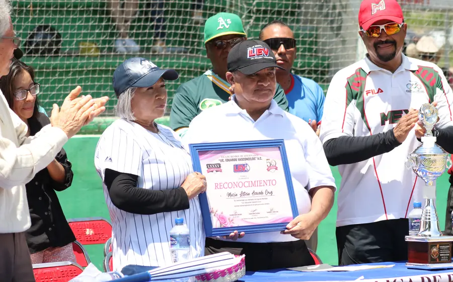 El presidente de la Liga Vasconcelos entrega un reconocimiento a Lety Acevedo durante la ceremonia inaugural del 85º torneo deportivo.