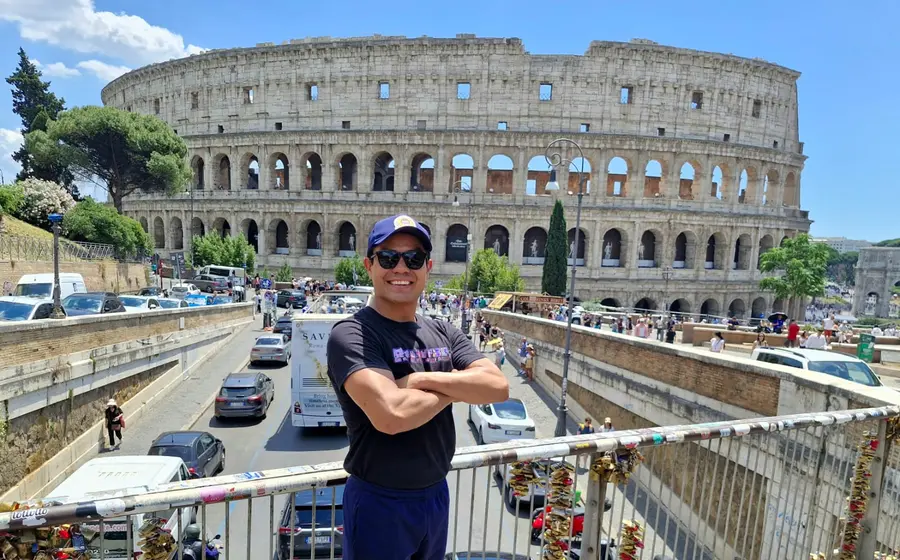 El luchador oaxaqueño Paul Lara, conocido como Rasputín, posa de pie frente al histórico Coliseo Romano en Italia.