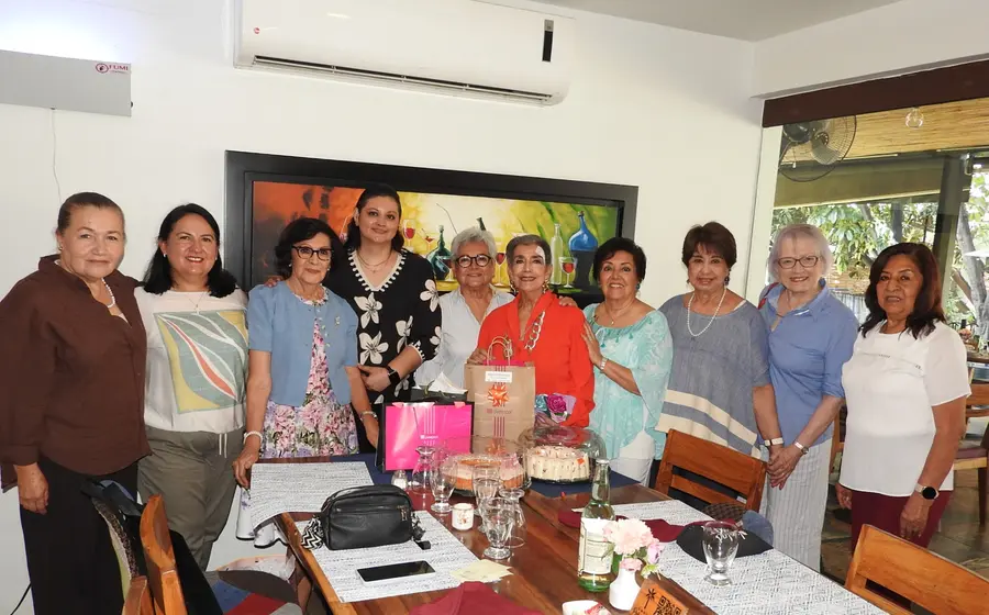 La maestra Lupita Aquino posa sonriente en el centro durante la emotiva celebración de su cumpleaños, rodeada por su grupo de amigas.