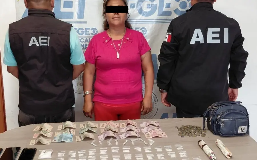 Una mujer detenida es presentada por las autoridades junto a una mesa donde se exhibe la presunta droga y el dinero asegurado durante el operativo.