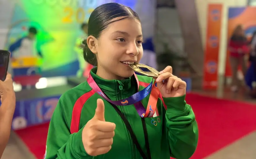 La atleta Aixa Mané Cruz Medina celebra con una gran sonrisa mientras posa con su medalla de oro de los juegos centroamericanos.