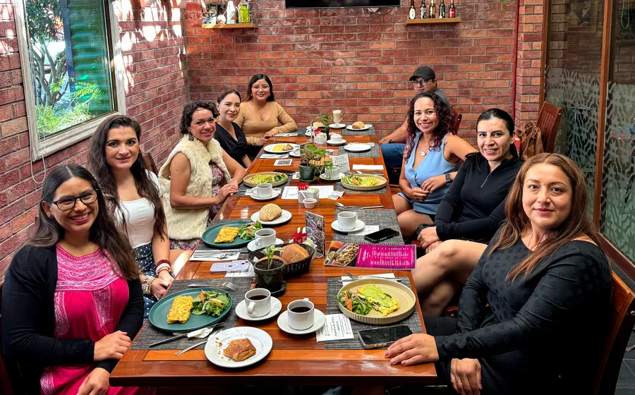 Clarisid Reyes Peláez, sentada al centro, celebra con miembros de AMEXME Oaxaca la próxima llegada de su bebé durante un desayuno en la ciudad.