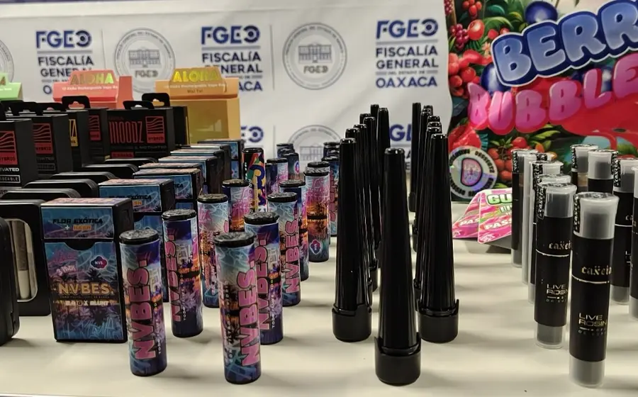 Paquetes de mariguana, dulces y cigarrillos exhibidos sobre una mesa, objetos que fueron asegurados durante un cateo en el Centro Histórico de Oaxaca.