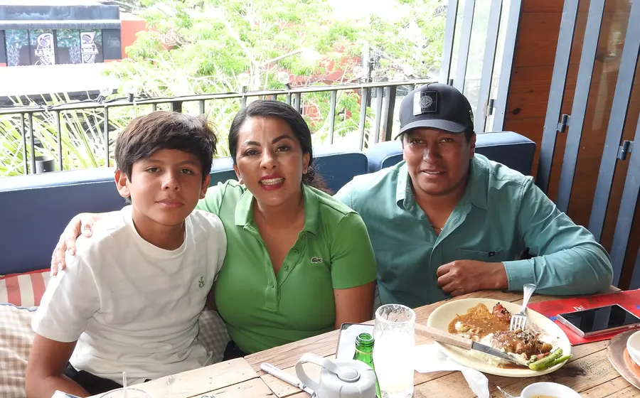Gener, Saymi y Jesús posan juntos y sonríen para la cámara, compartiendo un momento feliz durante una reunión social.