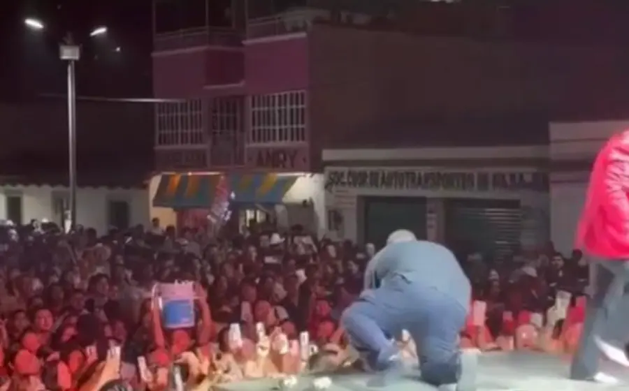 El cantante Lupillo Rivera de pie sobre el escenario usando solo calcetines, después de sufrir el robo de su calzado durante su presentación.