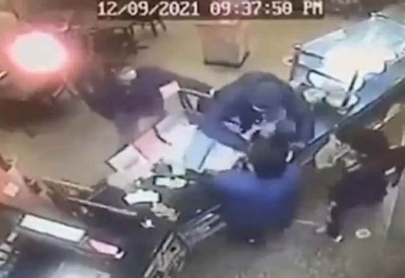 El cuerpo del delincuente quedó recostado sobre la caja registradora, mientras todos los presentes se alejan de la escena.