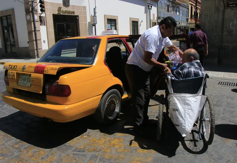 Persona en silla de ruedas abordando taxi