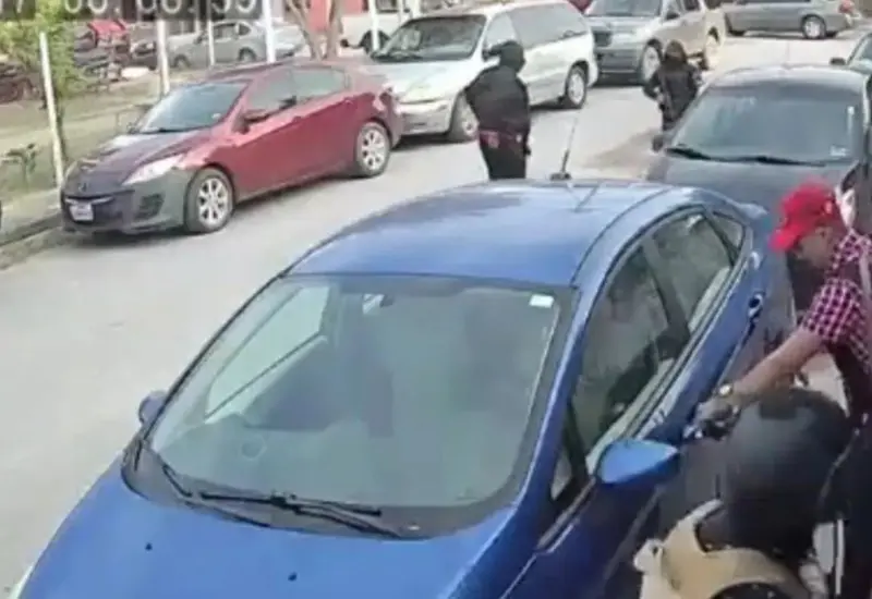 Un hombre y una mujer permanecen en la banqueta lamentando que los despojaron de un auto y no se percatan que delincuentes regresan y los amagan para que les entreguen las llaves de su segundo auto estacionado.